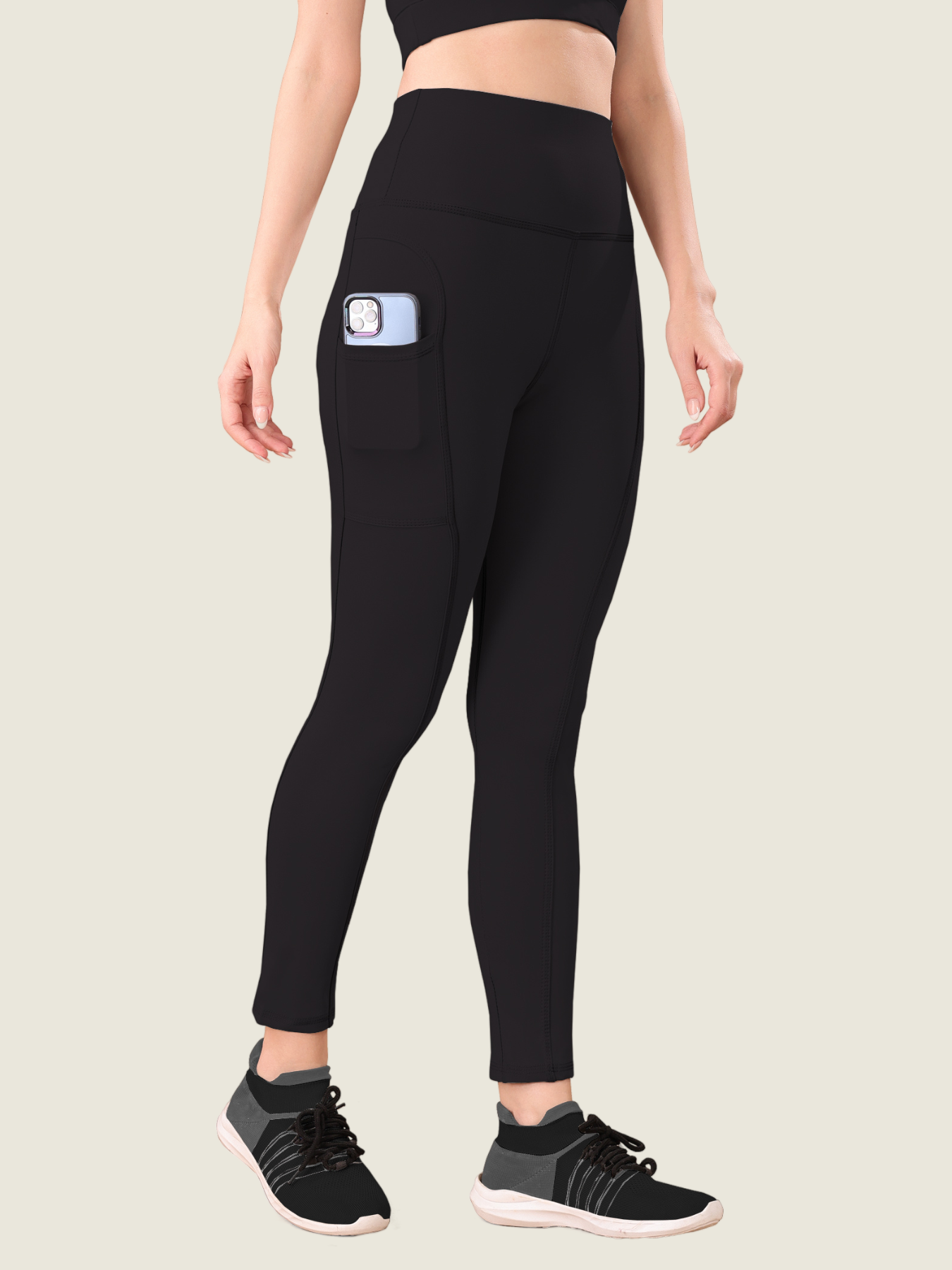 A person wearing high-waist black active pants with a visible brand logo on the upper left side of the waistband.